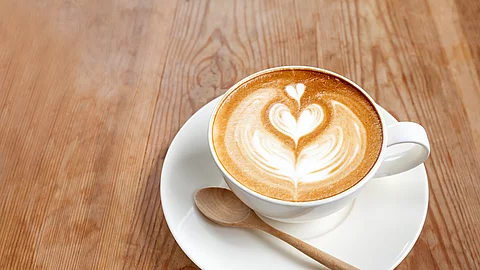 Eine Tasse Cappuccino auf Holztisch.