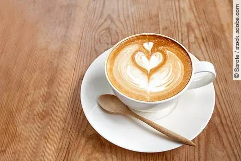 Eine Tasse Cappuccino auf Holztisch.