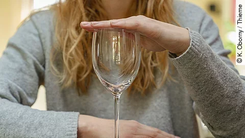 Frau hält Weinglas zu