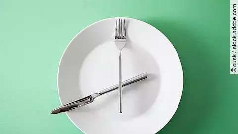 Intervallfasten, leerer Teller mit Besteck als Uhrzeiger