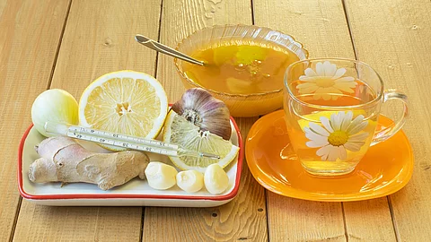 Teeglas und Holztablett mit frischem Ingwer und Zitrone