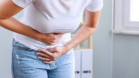 Junge Frau hält sich den schmerzenden Unterbauch.