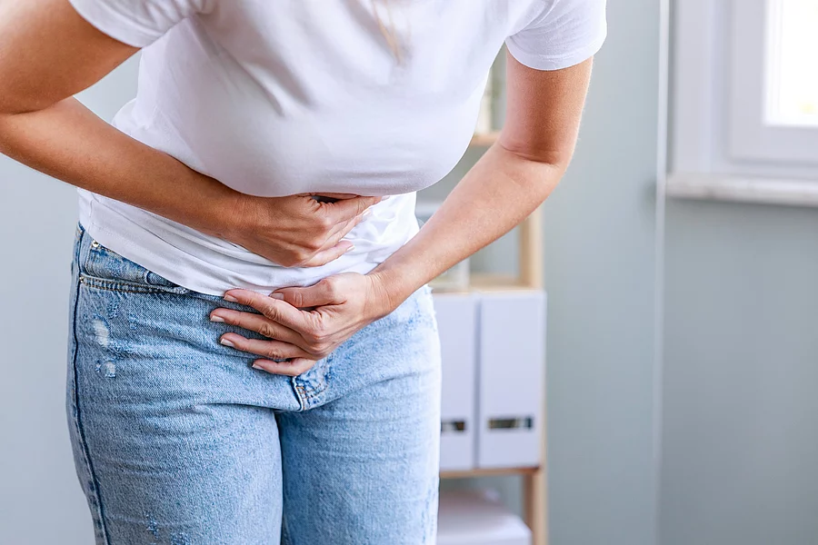 Junge Frau hält sich den schmerzenden Unterbauch.
