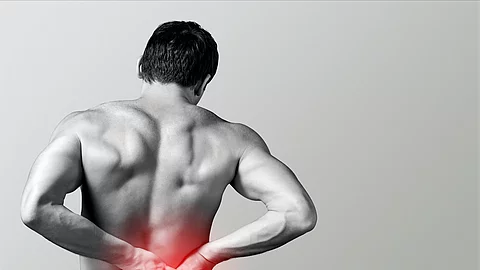 Chiropractic. Mann hält sich Schmerzpunkt mit Händen am Rücken