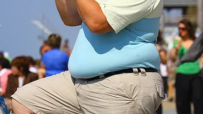 Man mit dickem Bauch in Seitenansicht auf Promenade, ohne Gesicht