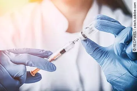 Eine Ärztin mit blauen Handschuhen zieht eine Impfung auf. 