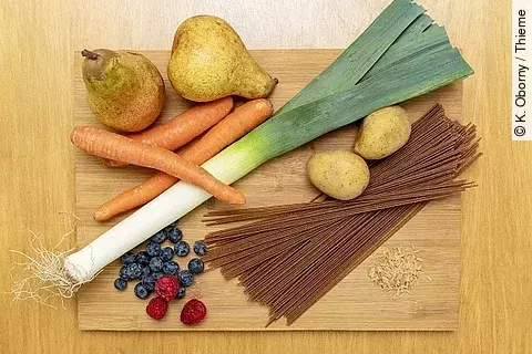 Birnen, Kartoffeln, Lauch, Vollkornspaghetti, Möhren, Beeren auf Holzbrett