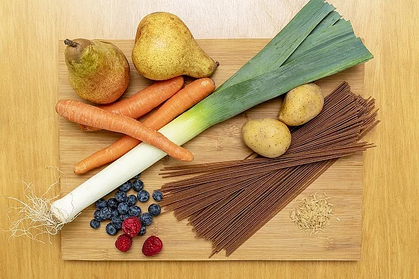 Birnen, Kartoffeln, Lauch, Vollkornspaghetti, Möhren, Beeren auf Holzbrett