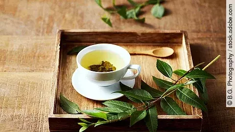 Grüner Tee in einer Tasse auf einem Tablett aus Holz