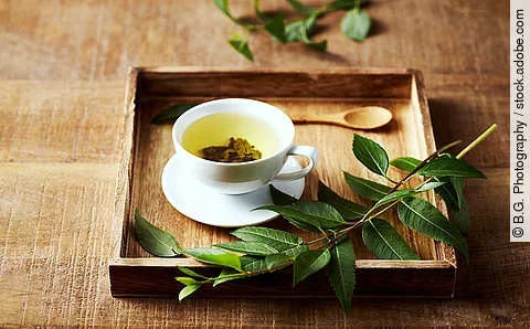 Grüner Tee in einer Tasse auf einem Tablett aus Holz