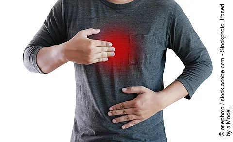 Mann mit grauem Shirt, der Magenbereich ist rot