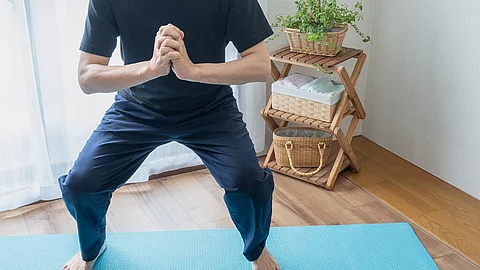 Mann macht Yoga auf einer blauen Yogamatte.