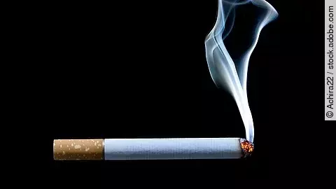 angezündete Zigarette vor schwarzem Hintergrund