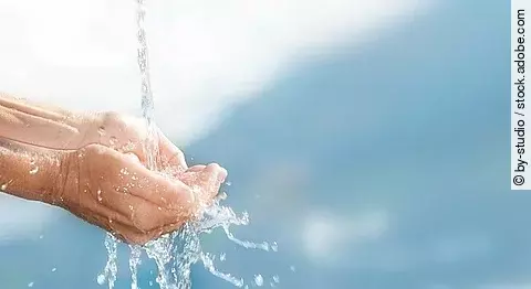 Wasserstrahl mit aufgehaltenen Händen.