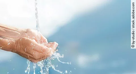 Wasserstrahl mit aufgehaltenen Händen.