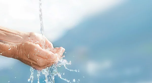 Wasserstrahl mit aufgehaltenen Händen.