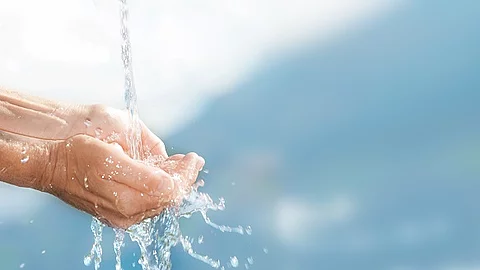 Wasserstrahl mit aufgehaltenen Händen.