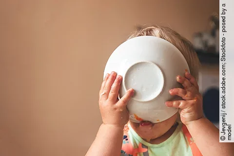 blondes Kind leckt Teller ab