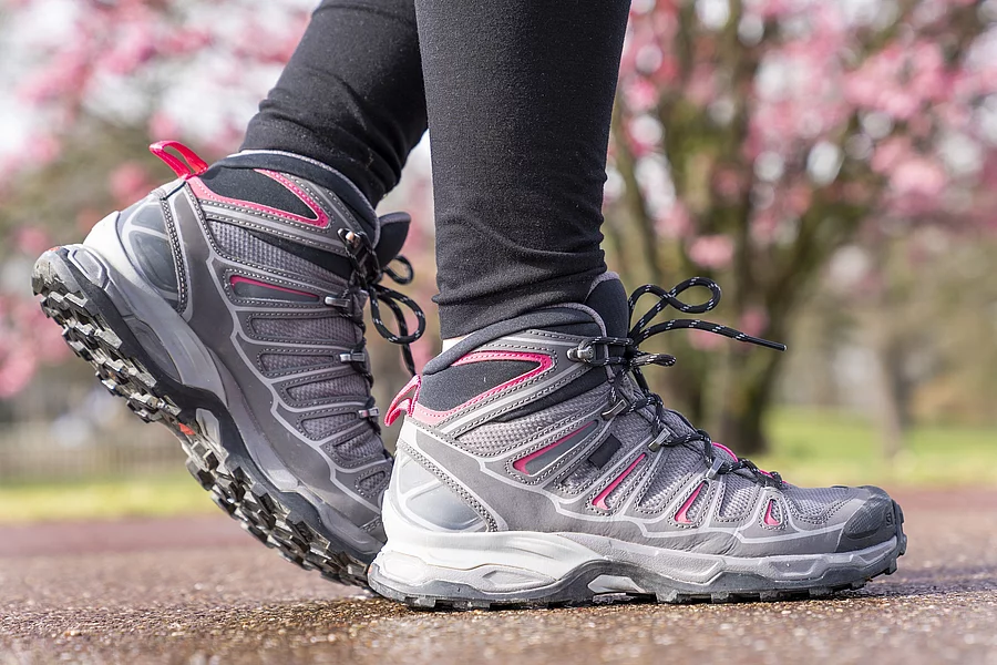 Frauenbeine in Leggings und Outdoorschuhen beim Nordic Walking draußen