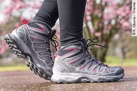 Frauenbeine in Leggings und Outdoorschuhen beim Nordic Walking draußen