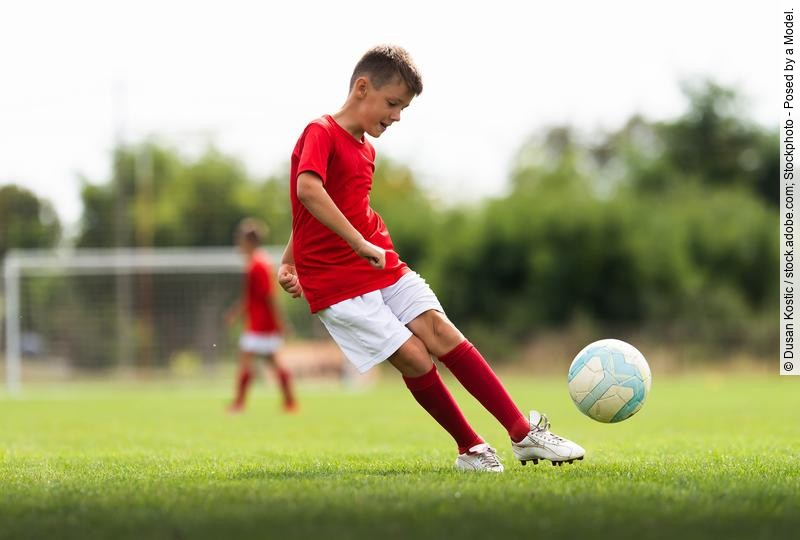 Junge spielt Fußball auf dem Fußballfeld
