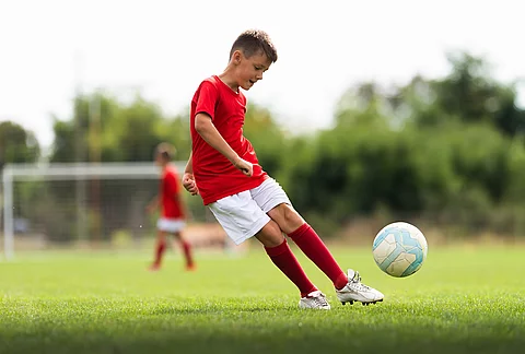 Junge spielt Fußball auf dem Fußballfeld