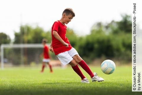 Junge spielt Fußball auf dem Fußballfeld