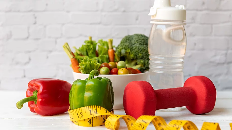 Symbolbild Gesunder Lebensstil: Gemüse, Hantel, Maßband