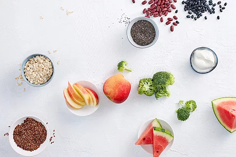 Obst, Hülsenfrüchte und Gemüse in kleinen weißen Schälchen auf einer weißen Oberfläche