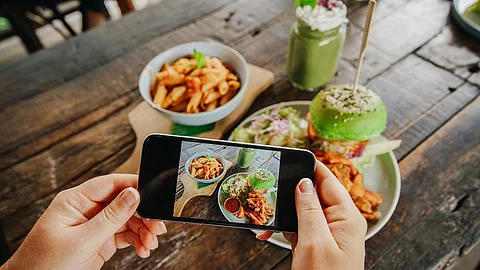 Frauenhand fotografiert Essen auf Holztisch