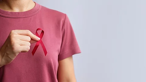 Burgundy Red Ribbon for March multiple myeloma Cancer and December World Aids Day Awareness month. Healthcare and world cancer day concept Frau im roten T-Shirt hält Brustkrebsschleife