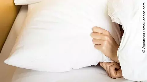 Frau im Bett, Kopfkissen über den Kopf gezogen