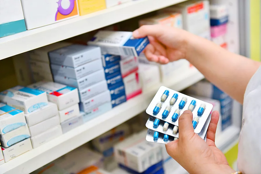Apothekerin räumt Arzneimittel ins Regal.