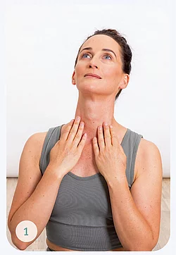 Frau in grauem Tanktop massiert sich das Gesicht