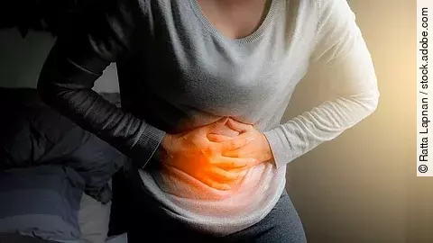 Eine Frau hält sich mit beiden Händen den Bauch. 