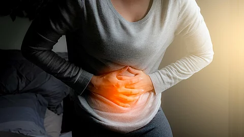 Eine Frau hält sich mit beiden Händen den Bauch. 