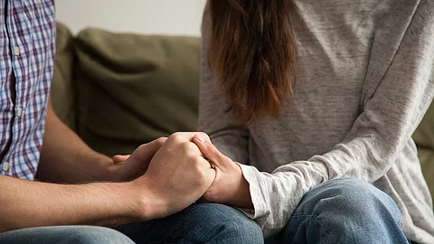Frau hält die Hände eines Mannes, um ihn zu trösten.