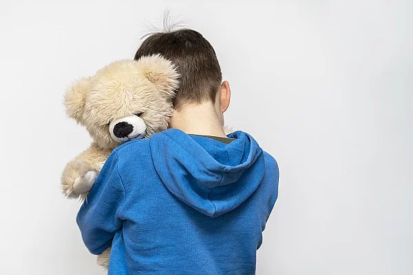 Ein Junge umarmt seinen Teddybär. 