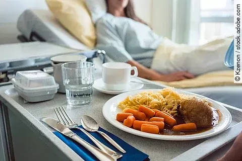Essen wird einem Patienten im Krankenhaus ans Bett serviert