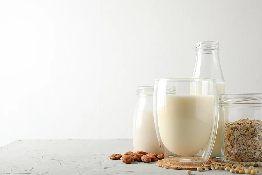 Bootle and glass of different types milk on gray background, space for text Flasche und Glas mit unterschiedlichen Milchsorten