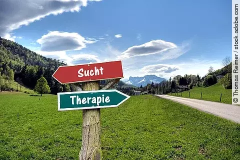 2 Wegweiser vor Berglandschaft: links: Sucht, rechts: Therapie