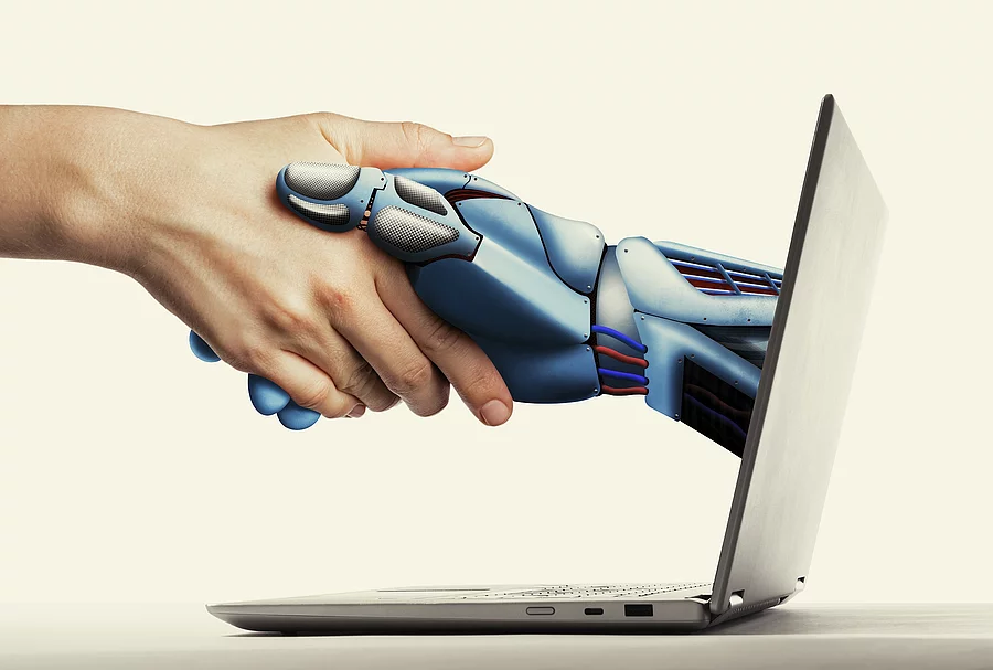 Handschlag einer KI-Hand aus Laptop heraus 