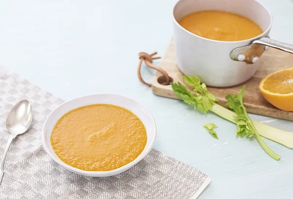 Kartoffelsuppe in einem weißen Teller. Im Hintergrund steht der Topf mit Kartoffelsuppe.