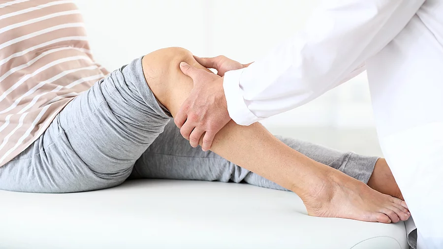 Arzt untersucht die Beine einer Frau