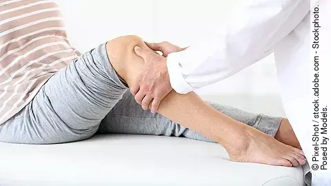 Arzt untersucht die Beine einer Frau