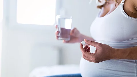 Pregnant woman taking medication Schwangere Frau nimmt Nahrungsergänzung ein.