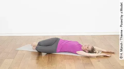 Frau liegt auf dem Rücken, Beine aufgestellt unf nach links gedreht