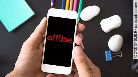 Ein Mann hält ein Smartphone in der Hand. Auf dem schwarzen Bildschirm steht in roter Schrift: offline. 