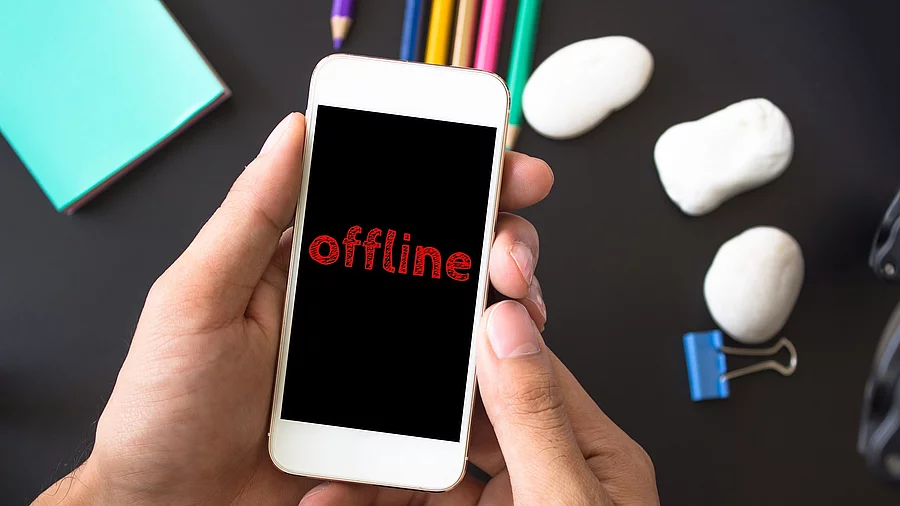Ein Mann hält ein Smartphone in der Hand. Auf dem schwarzen Bildschirm steht in roter Schrift: offline. 
