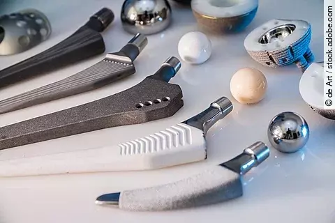 Auf einem Tisch liegen Hüftprothesen aus verschiedenen Materialien. 